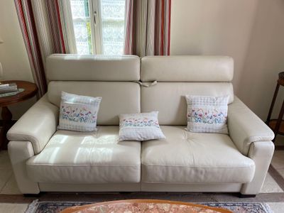 a white leather couch with pillows on it in a living room