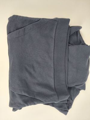 une pile de pulls gris posée sur une surface blanche