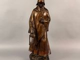 statue en bronze représentant un homme coiffé d'un chapeau et vêtu d'un manteau, tenant un seau