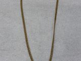 a gold necklace with a chain on a white surface