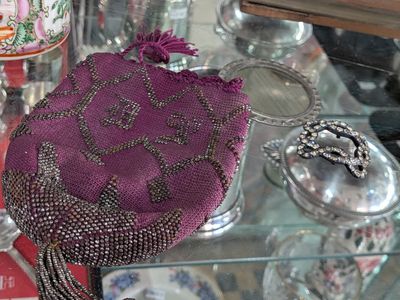 un sac à main violet posé sur une table en verre, à côté d'autres objets