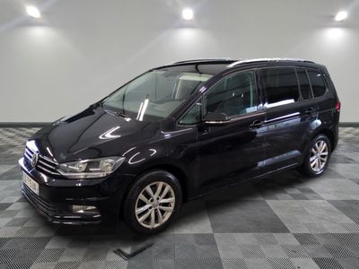La Volkswagen Touran noire est garée sur un sol en carrelage à damier.