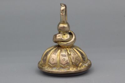 une clochette en or sur laquelle est perché un oiseau
