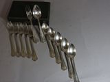 un tas de cuillères en argent et de petites cuillères posées sur une table