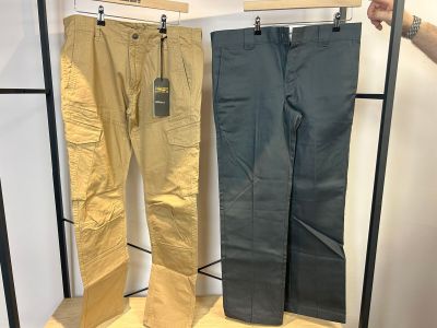 deux pantalons pour homme suspendus à un portant dans un magasin de vêtements