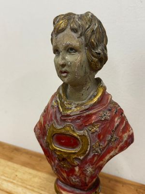 une petite statue représentant un jeune garçon, posée sur une table en bois