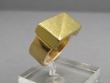 une image représentant une bague en or posée sur un bloc de verre transparent
