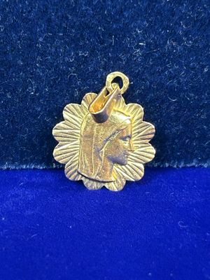 une image représentant un pendentif en or orné d'une tête de cheval sur fond bleu