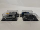 two black die cast cars in clear plastic boxes on a white surface