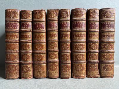 several old books are lined up on a shelf in a row