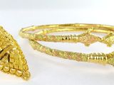 two pieces of gold colored jewelry on a white surface