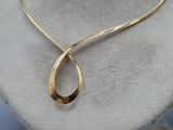 gold plated necklace on a mannequin neck with a curved design