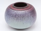 a purple and blue vase sitting on a white surface