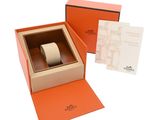 an orange box with a watch inside of it on a white surface