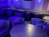 des canapés et des tables violets dans une pièce faiblement éclairée par des lumières bleues