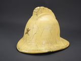an old yellow helmet with a bird on it on a black background