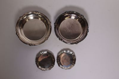 three silver plates and a mirror on a white surface