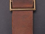a brown leather belt with a brass buckle on a black background