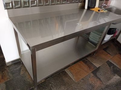 une table en acier inoxydable avec un plateau en verre dans une cuisine