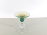 a small glass cup with a green rim on a table