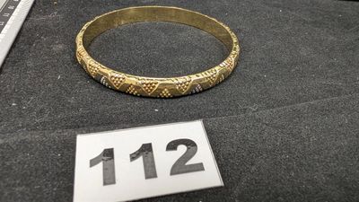 un bracelet en or posé sur une table à côté d'un clavier