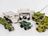 Plusieurs véhicules militaires et camions miniatures sont alignés sur une surface blanche