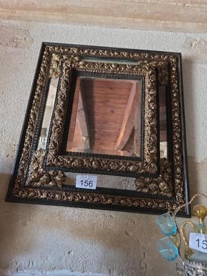 un miroir accroché au mur à côté d'un vase de fleurs