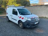 La camionnette blanche est garée sur le parking, près d'un mur.