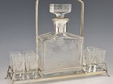 an antique silver plated glass decanter with four glasses on a tray