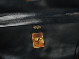 black leather bag with gold hardware on it sitting on a table