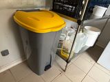 a trash can sitting next to a refrigerator in a kitchen