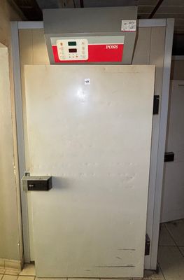 a white refrigerator sitting in a room with a tiled floor