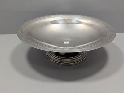 un plateau en argent posé sur un support en argent, sur une table