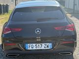 the rear end of a black mercedes cla parked in a gravel lot
