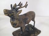 bronze sculpture of a deer with antlers standing on a base