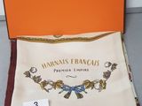 an orange box containing a scarf and a handkerchief with a picture of a bird on it