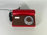 a red phone on a white table with a cord