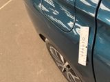 a sticker on the door of a blue car that is parked in a parking lot