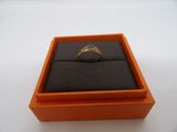 une boîte orange contenant une bague, posée sur une surface blanche