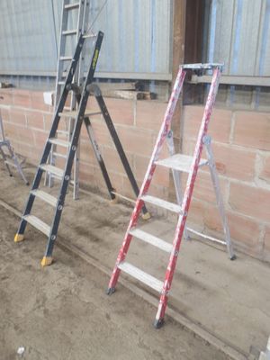 Plusieurs échelles sont alignées contre un mur de briques dans un immeuble