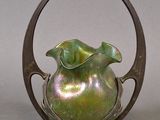 a green vase sitting on top of a metal stand