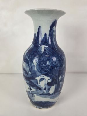un vase bleu et blanc posé sur une table blanche