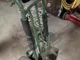 a green hand truck with a red handle in a garage