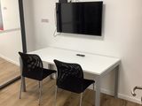 a white table with two black chairs and a flat screen tv on the wall