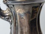 a silver tea pot with a lid on a table