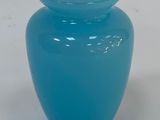un vase bleu muni d'un couvercle, posé sur une surface blanche