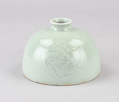 un vase vert orné d'un lion, posé sur une table