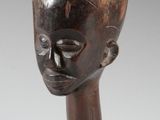 une image représentant un vase en forme de tête en bois posé sur une surface blanche