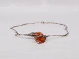 a close up of a silver bracelet with an orange glass bead