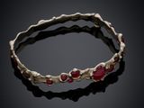 un gros plan d'un bracelet orné de pierres rouges sur un fond noir